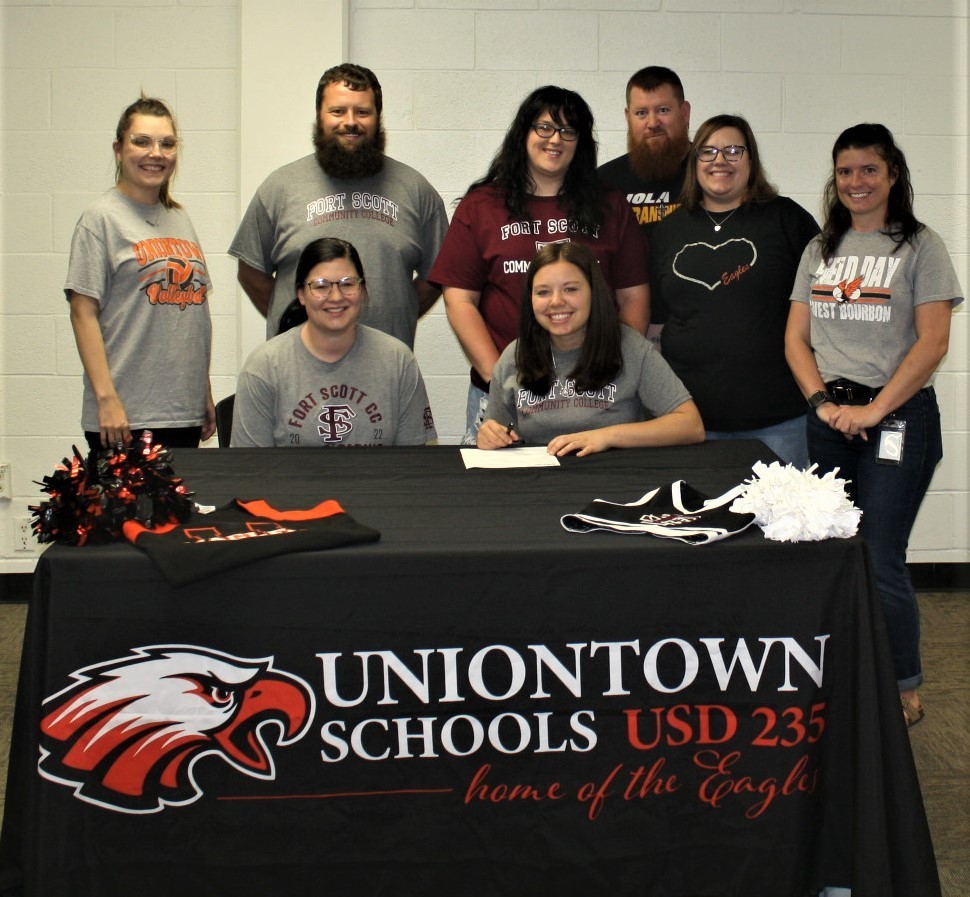 Picture of senior student Camryn Davis and her family while Camryn is signing a  letter of intent to cheer for Fort Scott Community College in 2022-23.