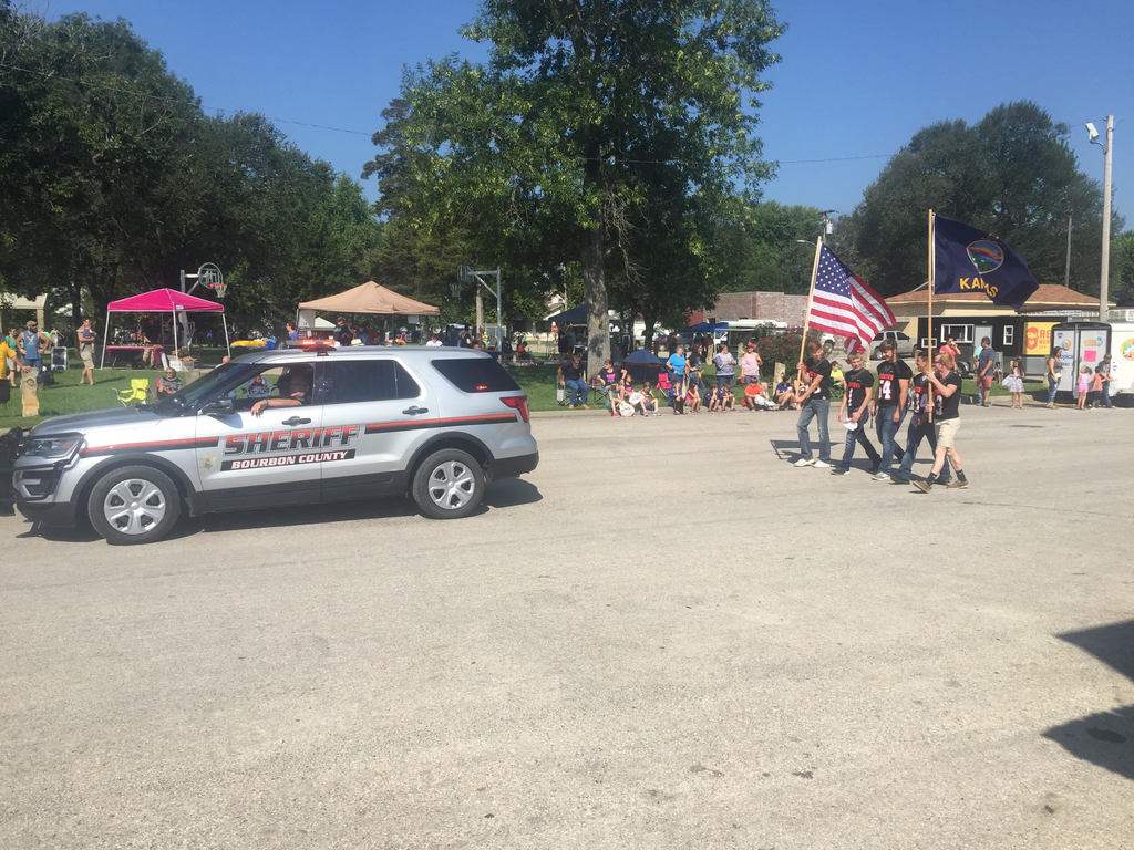 Sheriff Martin and members of HS Football team carrying the colors are leading the Old Settler's Day Parade in Uniontown, KS